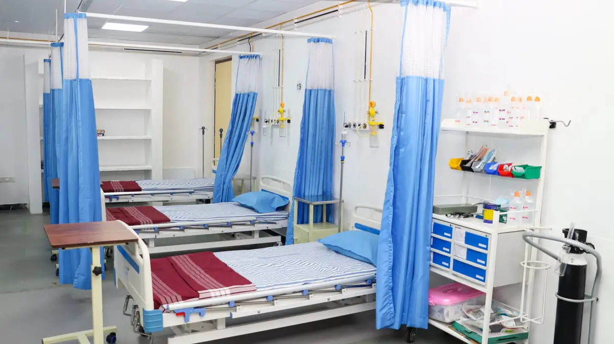 Hospital beds with curtains, an oxygen supply and a supply trolley